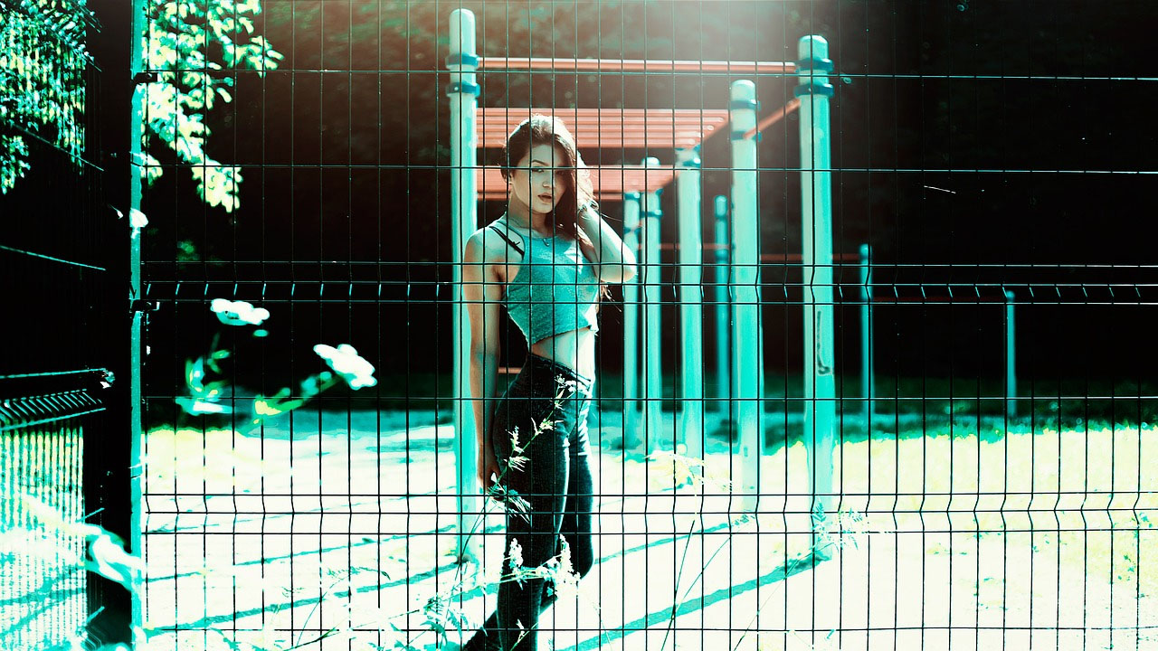 women in jeans behind fence